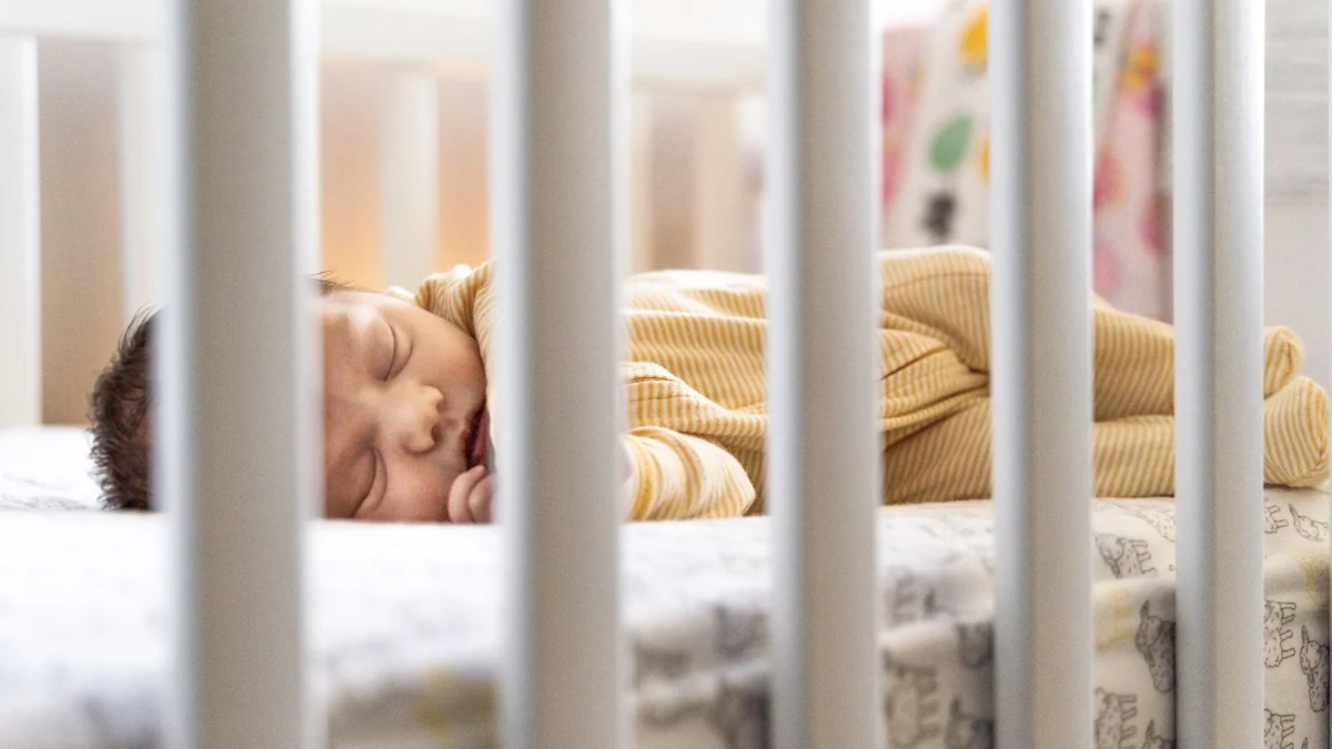 Bébé endormi dans son lit à barreaux